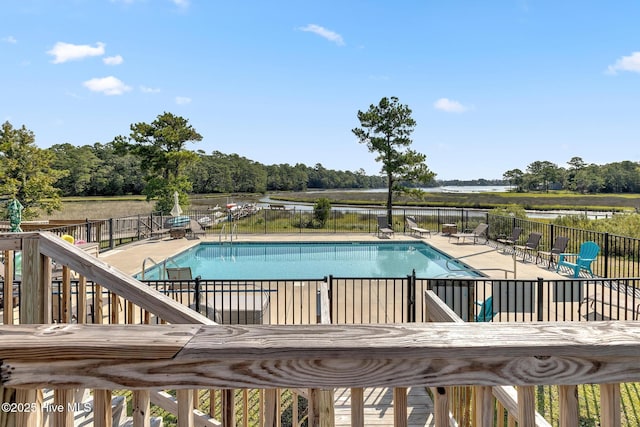 community pool featuring a water view, fence, and a patio area