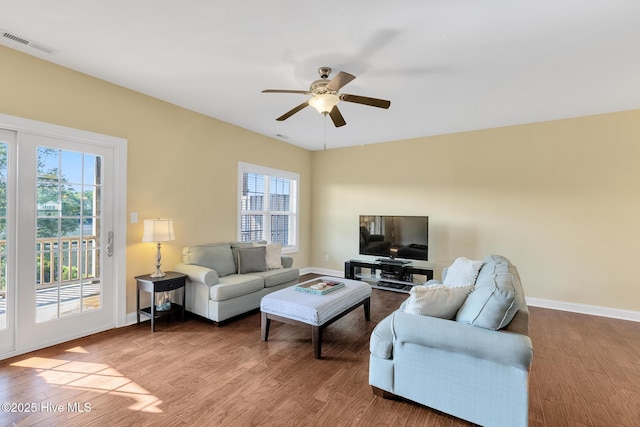 living area with visible vents, a healthy amount of sunlight, baseboards, and wood finished floors