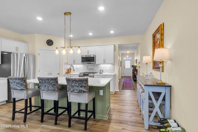 400 Frida Rd, New Bern, NC 28560 - kitchen featuring stainless steel appliances, light countertops, an island with sink, light wood finished floors, and white cabinets