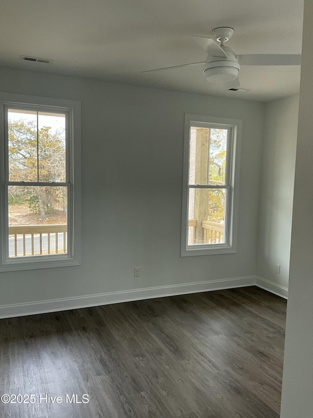 unfurnished room with visible vents, baseboards, dark wood-type flooring, and ceiling fan