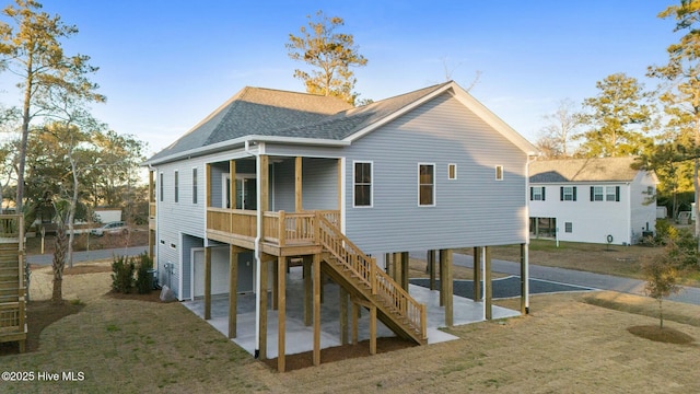 back of house with stairway, a patio, a carport, and roof with shingles