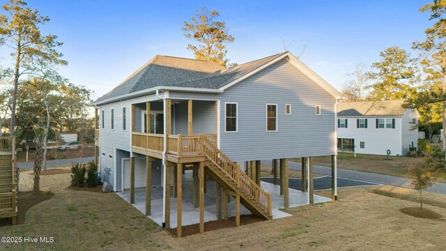 7105 E Yacht Dr, Oak Island, NC 28465 - rear view of property featuring a carport, roof with shingles, a patio area, stairway, and a yard