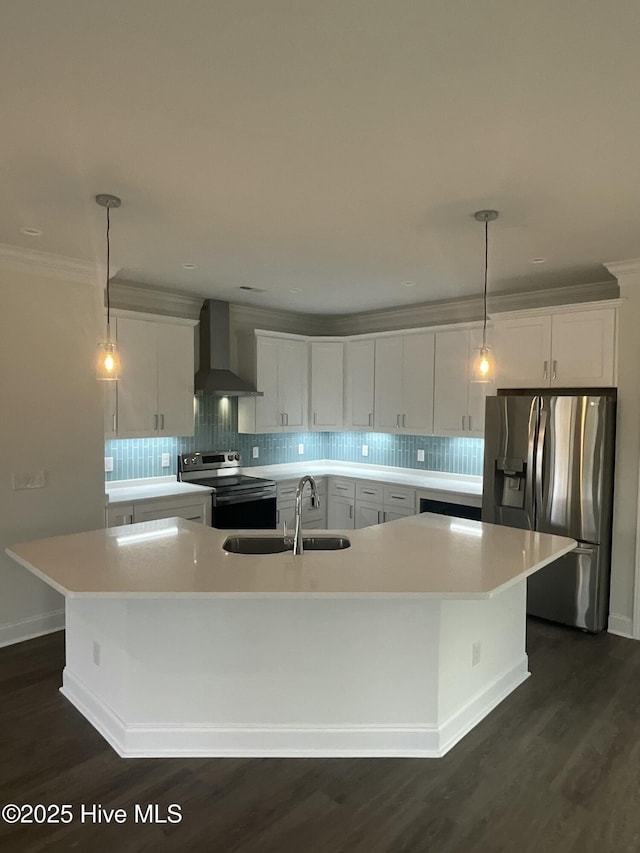 kitchen with a spacious island, wall chimney range hood, light countertops, appliances with stainless steel finishes, and a sink