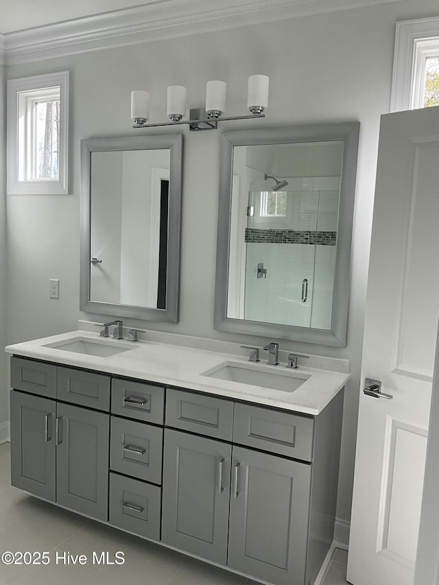 full bath with double vanity, a shower stall, crown molding, and a sink