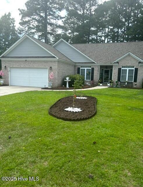 single story home with an attached garage, brick siding, driveway, and a front lawn