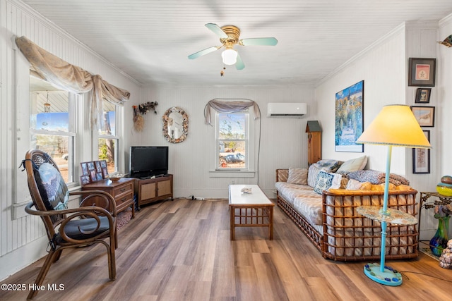 sitting room with crown molding, a ceiling fan, an AC wall unit, and wood finished floors