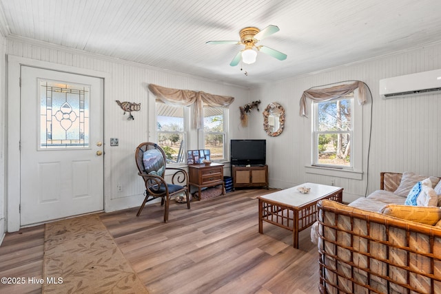 sitting room with light wood-style floors, a ceiling fan, plenty of natural light, and a wall mounted AC