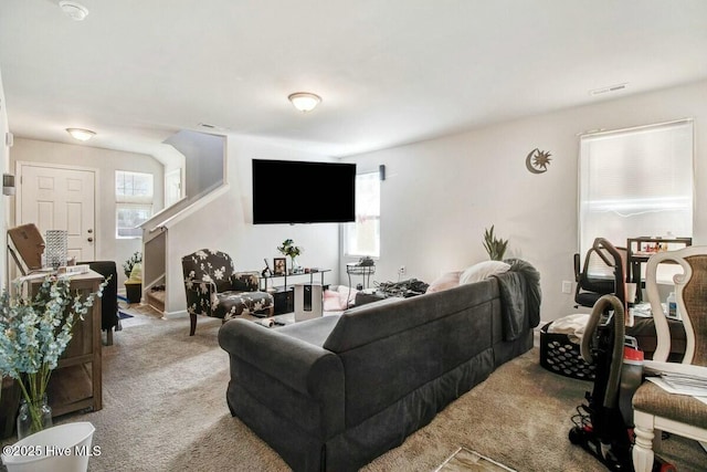 carpeted living area with stairs and visible vents