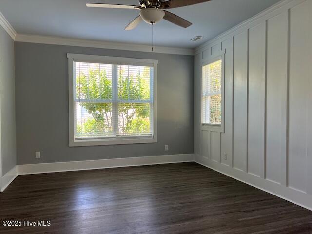 empty room with crown molding, baseboards, and dark wood-type flooring