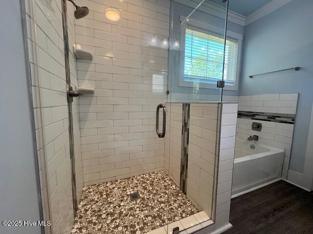 bathroom featuring a stall shower, crown molding, a garden tub, and wood finished floors