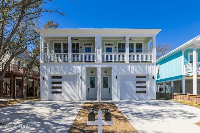 coastal inspired home featuring concrete driveway, board and batten siding, and a ceiling fan