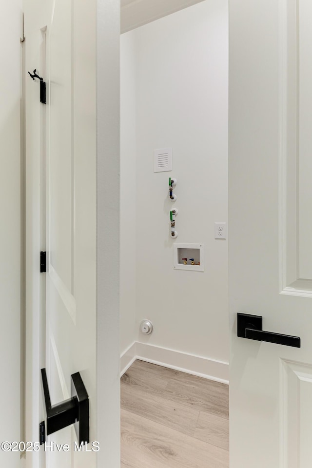 laundry area with laundry area, baseboards, washer hookup, and wood finished floors