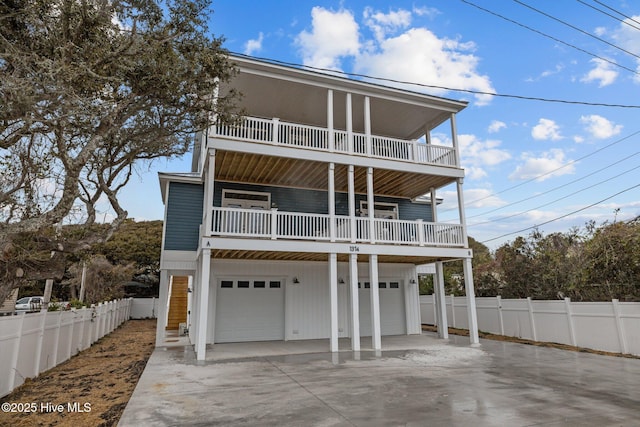 coastal inspired home with concrete driveway, an attached garage, and fence