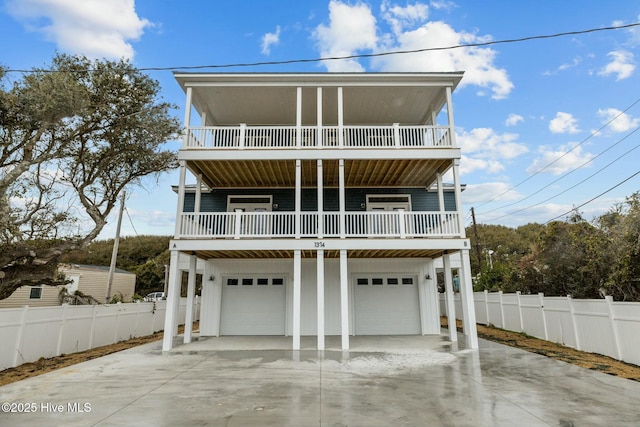 coastal home featuring driveway, a garage, and fence