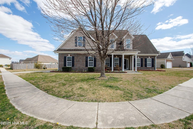 cape cod-style house with a front yard, fence, a porch, and brick siding