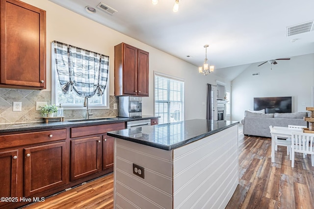 kitchen with light wood-style floors, a kitchen island, visible vents, and a sink
