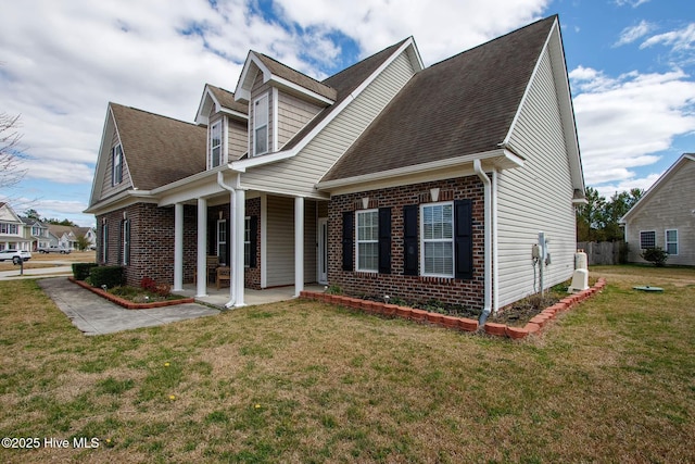 view of front of house with brick siding, a front lawn, and a shingled roof