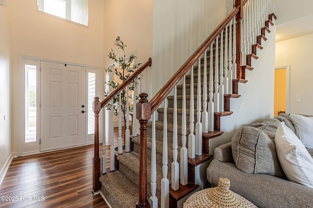 entrance foyer featuring a towering ceiling and dark wood finished floors