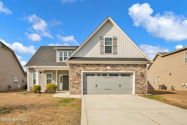 view of front of home with driveway, a garage, cooling unit, board and batten siding, and a front yard