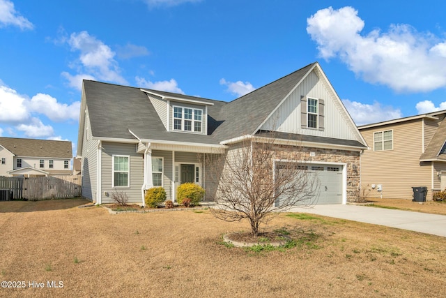 view of front facade with stone siding, concrete driveway, and fence