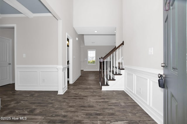 entrance foyer featuring dark wood-type flooring, a decorative wall, and stairs