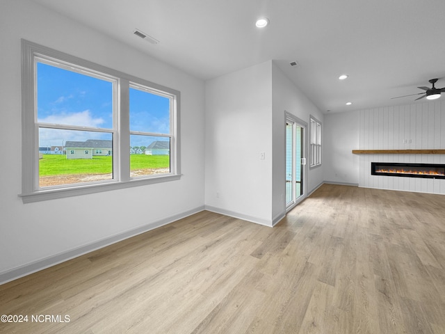 unfurnished living room with recessed lighting, wood finished floors, visible vents, baseboards, and a glass covered fireplace