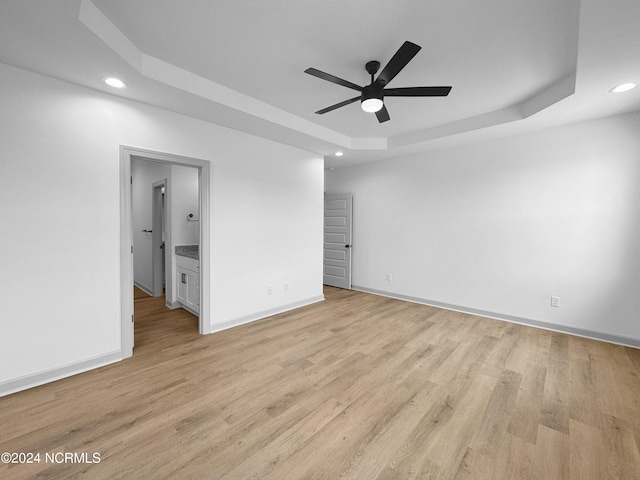 interior space with recessed lighting, a raised ceiling, light wood-style flooring, and baseboards