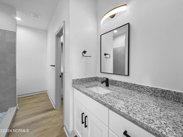 full bathroom featuring vanity, visible vents, wood finished floors, and tiled shower