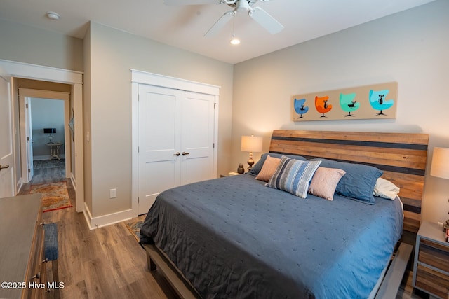 bedroom with ceiling fan, a closet, wood finished floors, and baseboards