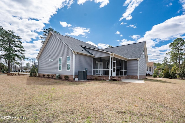 back of house featuring central air condition unit, a sunroom, and a lawn