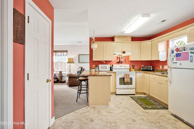 kitchen with plenty of natural light, under cabinet range hood, a breakfast bar, and white appliances