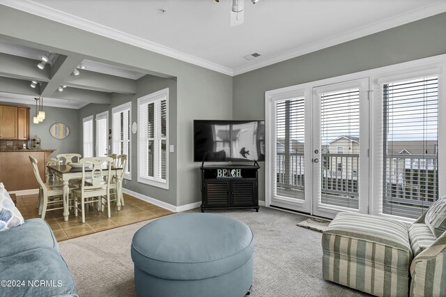 tiled living area with a healthy amount of sunlight, visible vents, baseboards, and crown molding