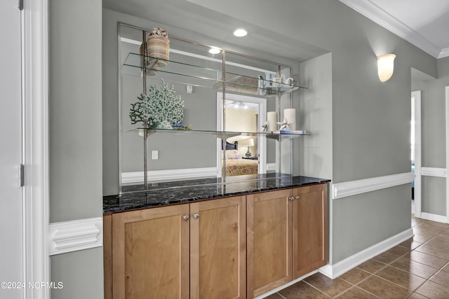 bar featuring baseboards, ornamental molding, and dark tile patterned flooring