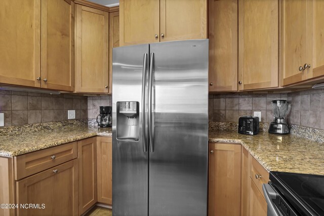 kitchen featuring backsplash, stainless steel fridge with ice dispenser, and light stone countertops