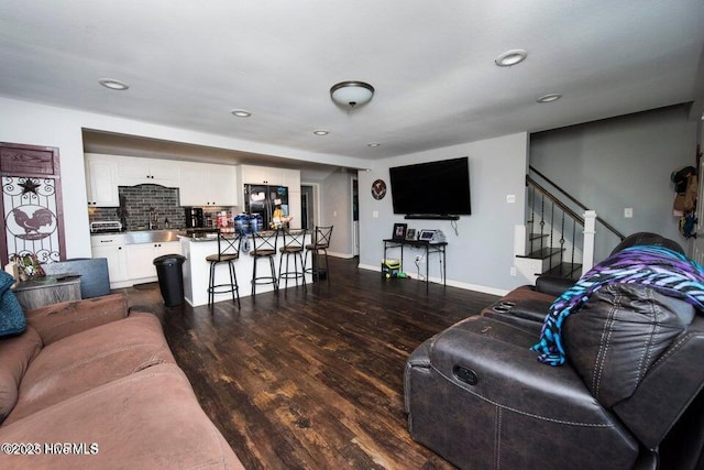 living room with recessed lighting, dark wood finished floors, baseboards, and stairs