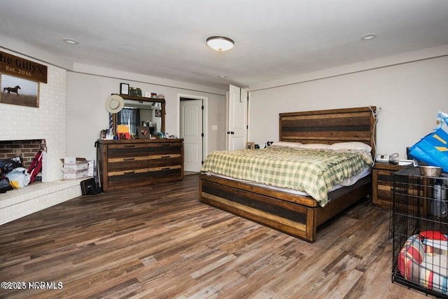 bedroom with a brick fireplace and wood finished floors