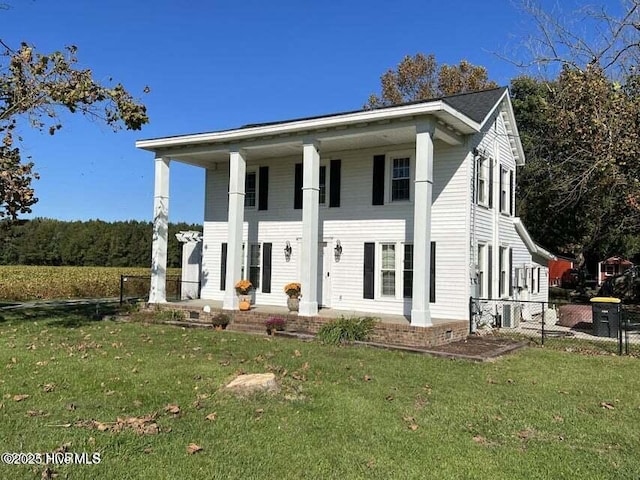 greek revival house featuring covered porch, a front lawn, and fence