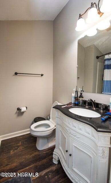 full bath featuring toilet, wood finished floors, vanity, baseboards, and a shower with curtain