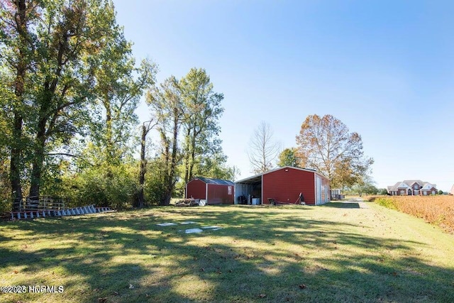 view of yard featuring driveway, a detached garage, a pole building, and an outbuilding