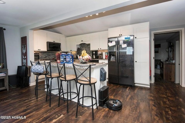 kitchen featuring black appliances, white cabinetry, decorative backsplash, and a breakfast bar area