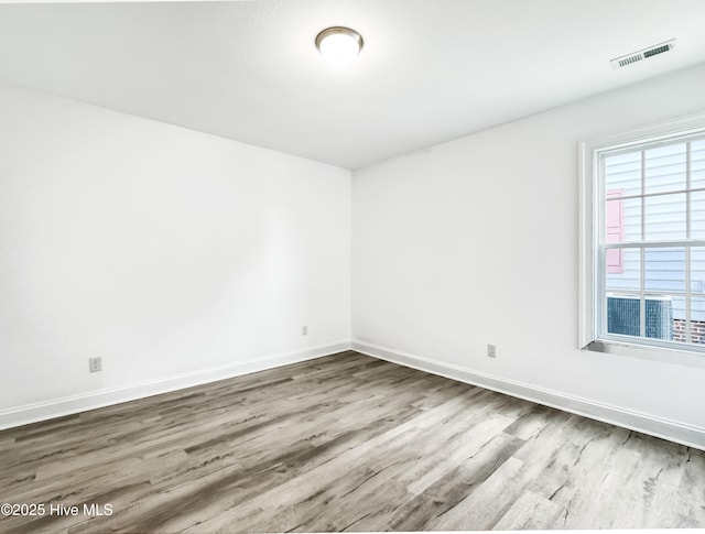 spare room featuring visible vents, baseboards, and wood finished floors