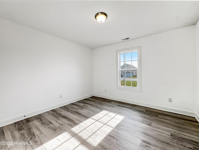 spare room with visible vents, baseboards, and dark wood finished floors