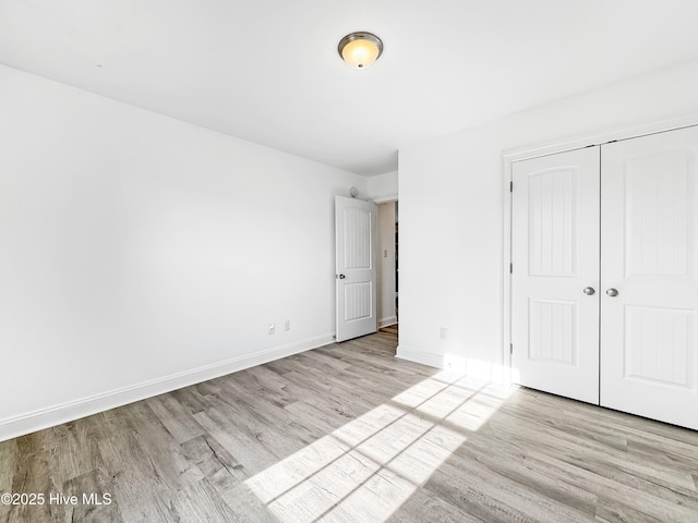 unfurnished bedroom featuring a closet, baseboards, and wood finished floors