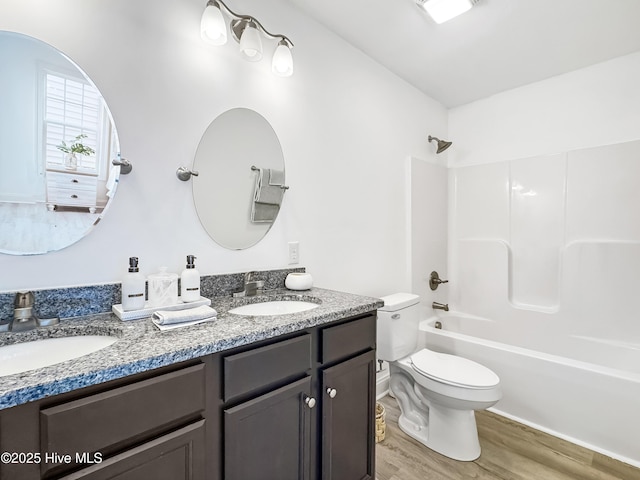 bathroom with double vanity, wood finished floors, a sink, and toilet