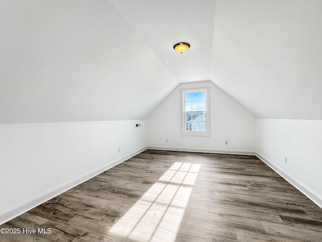 additional living space featuring lofted ceiling, wood finished floors, and baseboards