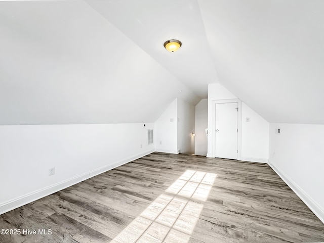 additional living space featuring lofted ceiling, baseboards, visible vents, and wood finished floors