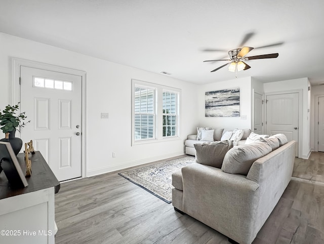 living room with a ceiling fan, baseboards, visible vents, and wood finished floors