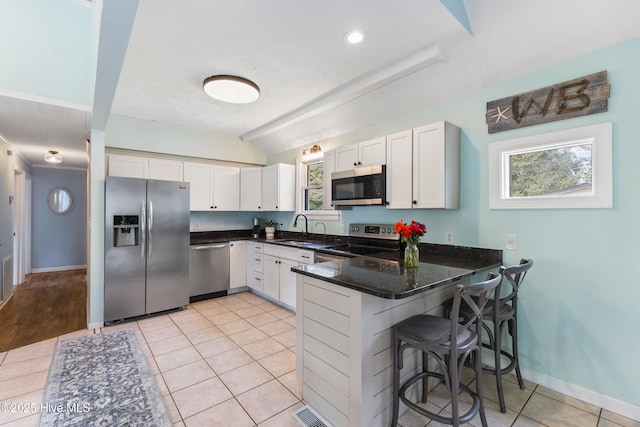 kitchen with visible vents, a sink, white cabinetry, stainless steel appliances, and a peninsula