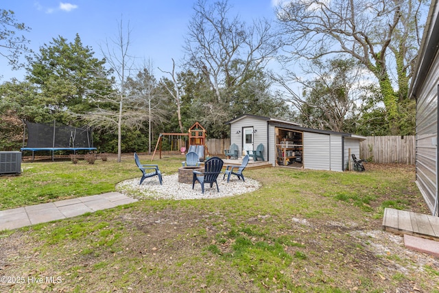 view of yard with an outbuilding, a trampoline, fence, a playground, and an outdoor fire pit