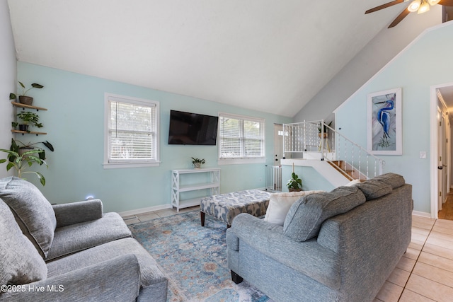 living room with tile patterned floors, a ceiling fan, baseboards, stairs, and vaulted ceiling